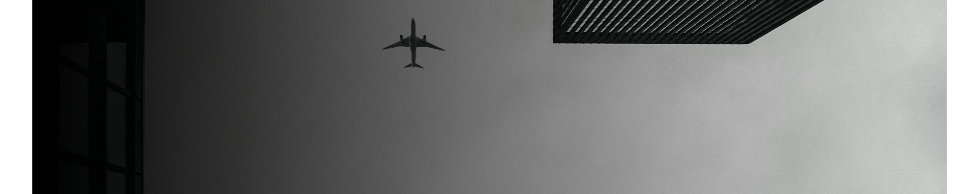 Aircraft passing between modern buildings